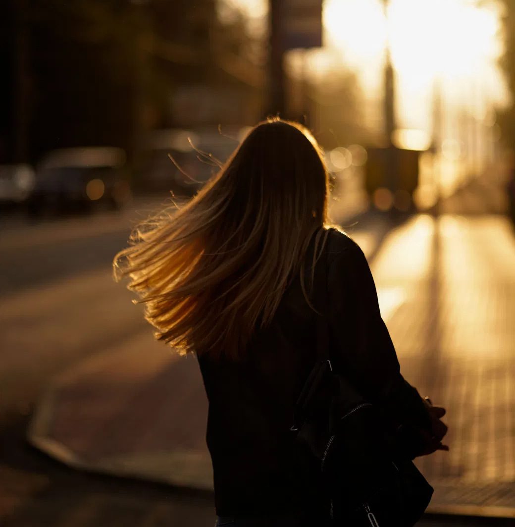 A woman walking a city street alone at golden hour