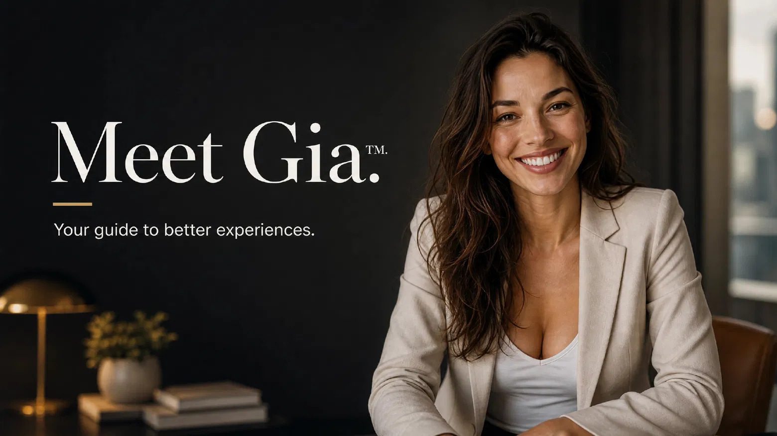 Warm studio portrait of Gia smiling at a desk against a dark backdrop.