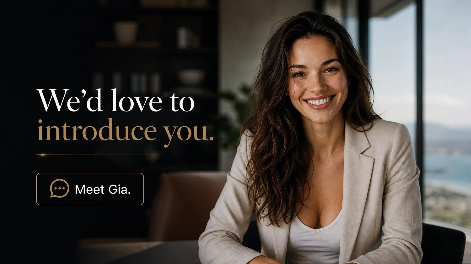 Gia smiling warmly at a desk in front of a coastal window.